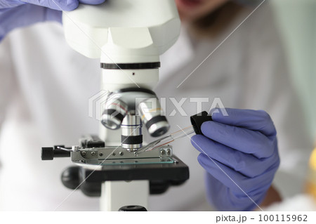 Scientist works with pipette and microscope in research laboratory. 100115962