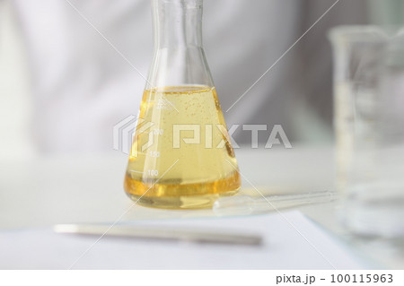 Close-up of flask with yellow liquid on table of research laboratory. 100115963