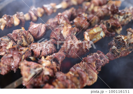 Close-up of several skewers with grilled juicy meat in smoke. Close-up of several skewers with grilled juicy meat in smoke. 100116151