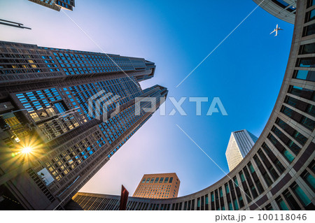 日本の東京都市景観 ダイヤモンド都庁と航空機。夕方の東京都庁と都心上空を通過する航空機。航空需要回復 日本の東京都市景観 ダイヤモンド都庁と航空機。夕方の東京都庁と都心上空を通過する航空機。航空需要回復 100118046