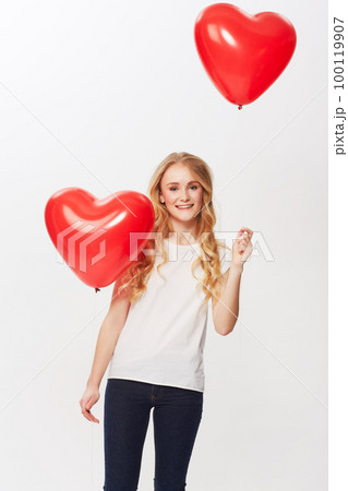 Love is in the air. Cropped view of a young woman holding a red heart in a studio. 100119907