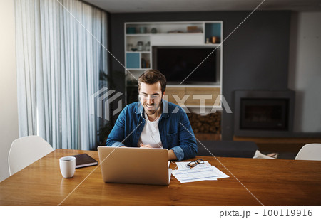 Its still business as usual even at home. Shot of a handsome young businessman sitting down and using his laptop to take a video call while working from home. 100119916