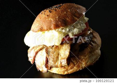 タルタルソースがはみ出てるベーコンとレタスとトマトがはさまったBLTバーガーを黒背景で撮影 タルタルソースがはみ出てるベーコンとレタスとトマトがはさまったBLTバーガーを黒背景で撮影 100120121