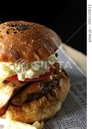 タルタルソースがはみ出てるベーコンとレタスとトマトがはさまったBLTバーガーとポテトを黒背景で撮影 100120613