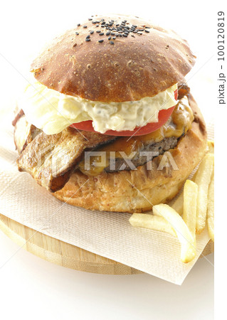 タルタルソースがはみ出ててベーコンとレタスとトマトがはさまったBLTバーガーとポテトを白背景で撮影 100120819