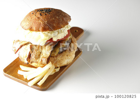 タルタルソースがはみ出ててベーコンとレタスとトマトがはさまったBLTバーガーとポテトを白背景で撮影 100120825