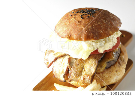 タルタルソースがはみ出ててベーコンとレタスとトマトがはさまったBLTバーガーとポテトを白背景で撮影 100120832