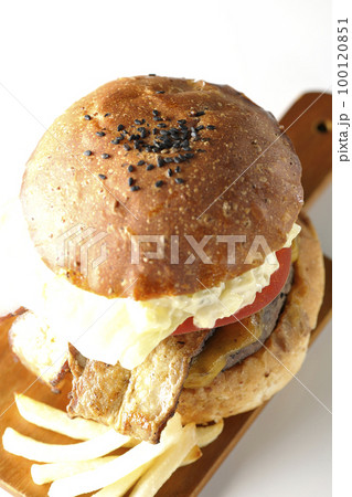 タルタルソースがはみ出ててベーコンとレタスとトマトがはさまったBLTバーガーとポテトを白背景で撮影 100120851