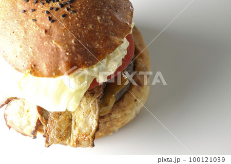 タルタルソースがはみ出ててベーコンとレタスとトマトがはさまったBLTバーガーを白背景で撮影 100121039