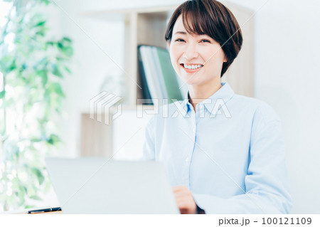 リビングでテレワークをするミドル女性 リビングでテレワークをするミドル女性 100121109