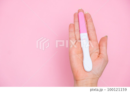 Female hand holding a positive pregnancy test on the pink background. Planning of pregnancy and motherhood concept with copy space Female hand holding a positive pregnancy test on the pink background. Planning of pregnancy and motherhood concept with copy space 100121159
