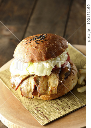 タルタルソースがはみ出ててベーコンとレタスとトマトがはさまったBLTバーガーとフライドポテト 100121160