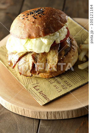 タルタルソースがはみ出ててベーコンとレタスとトマトがはさまったBLTバーガーとフライドポテト 100121164