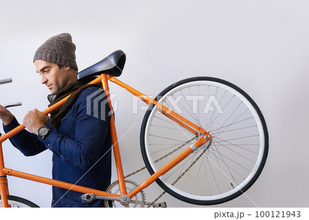 Getting to work by bike. Cropped shot of a trendy young man carrying his bicycle indoors. 100121943