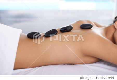 Step one to total relaxation. Shot o a young woman getting a hot rock treatment at a spa. 100121944