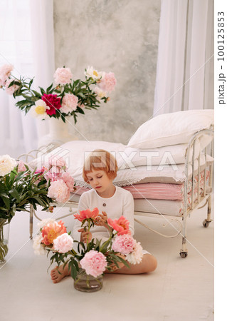 Girl 6-7 years old in a white dress holds a flower Girl 6-7 years old in a white dress holds a flower 100125853
