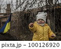 Little girl in front of defensive structures of Ukrainian army. War in Ukraine. Children and war concept. Support for Ukraine. Stop war. Humanitarian disaster concept. Ukrainian flag 100126920