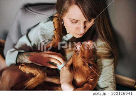 Young Woman Hugging Vizsla Dog at Home Young Woman Hugging Vizsla Dog at Home 100126941