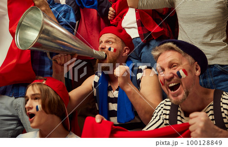 Live match. Football, soccer fans emotionally cheering up favourite france team. People wearing country's attributes, scarves and paints Live match. Football, soccer fans emotionally cheering up favourite france team. People wearing country's attributes, scarves and paints 100128849