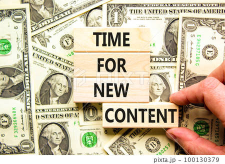 Time for new content symbol. Concept words Time for new content on wooden blocks. Beautiful background from dollar bills. Businessman hand. Business time for new content concept. Copy space. 100130379
