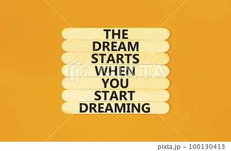 Start dreaming symbol. Concept words The dream starts when you start dreaming on wooden stick. Beautiful orange table orange background. Copy space. Motivational business start dreaming concept. 100130413