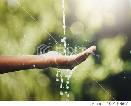 Hygiene, washing and saving water with hands against a green nature background. Closeup of one person holding out their palm to save, conserve and refresh with water in a park, garden or backyard 100130667