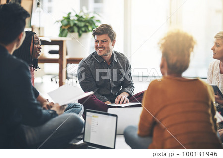 Creative business team in a meeting planning and brainstorming together while sitting on the floor. A group of colleagues or coworkers talking and discussing company ideas in a modern office 100131946