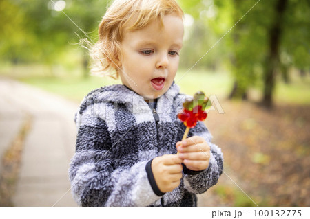 Funny child with candy lollipop, little boy eating big sugar lollipop outdoors 100132775