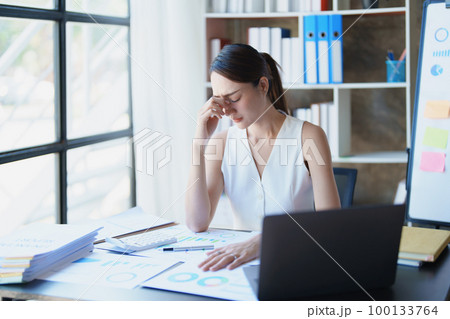 Portrait of sme business owner, woman using computer and financial statements Anxious expression on expanding the market to increase the ability to invest in business. 100133764