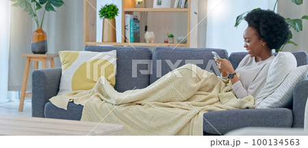 Happy black woman reading social media gossip on phone while relaxing on a sofa at home. Young African American female texting and sharing an interesting scandal, shocked about drama on the internet Happy black woman reading social media gossip on phone while relaxing on a sofa at home. Young African American female texting and sharing an interesting scandal, shocked about drama on the internet 100134563