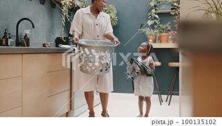 Laundry, mother and child helping with folding of clothes together in a house. Happy, excited and young girl giving help to her mom while cleaning clothing from a washing machine in their home Laundry, mother and child helping with folding of clothes together in a house. Happy, excited and young girl giving help to her mom while cleaning clothing from a washing machine in their home 100135102