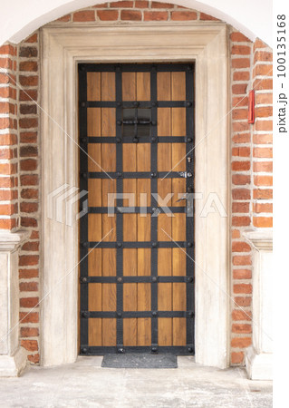 Old wooden brown house door. Gorgeous wooden door in the streets Krakow Poland. antique wooden door with wrought-iron Old wooden brown house door. Gorgeous wooden door in the streets Krakow Poland. antique wooden door with wrought-iron 100135168