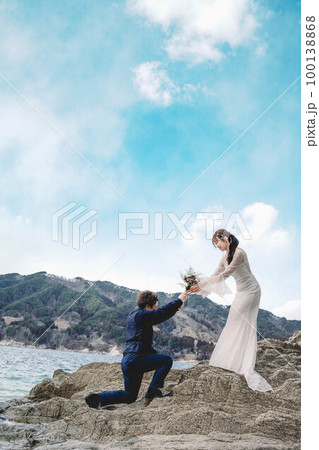 岸壁で花嫁に花束を渡す男性 100138868
