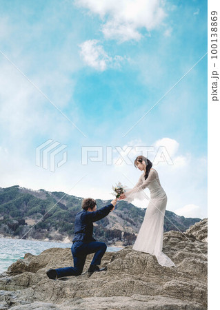 岸壁で花嫁に花束を渡す男性 100138869