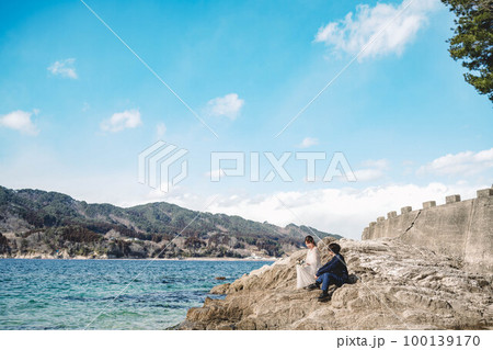青空の海で楽しそうにする新郎新婦 100139170