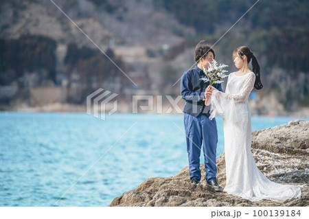 青空の海で楽しそうにする新郎新婦 100139184