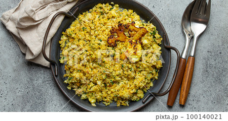 Fried cauliflower rice or couscous with dill on plate, healthy low carbohydrates vegetable side dish for keto diet and healthy low calories nutrition, rustic stone background 100140021