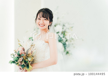 結婚式場でブーケを持つ花嫁・新婦の女性（カメラ目線） 100144495