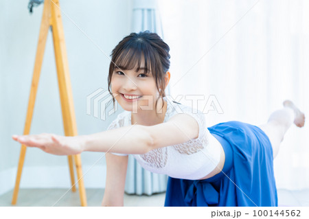 明るいリビングでヨガをする若い女性 明るいリビングでヨガをする若い女性 100144562