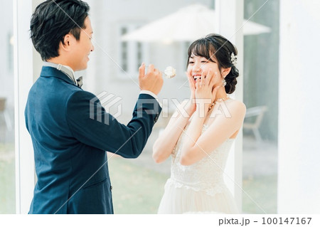 結婚式でファーストバイトをする新郎新婦(ウェディングケーキ・ケーキ入刀) 100147167