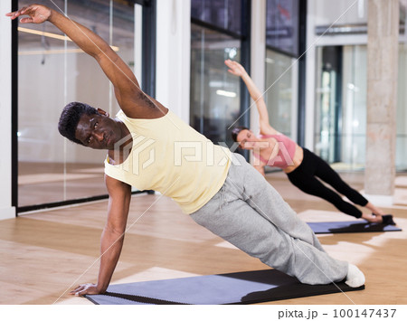 Man practicing pilates exercises at group class Man practicing pilates exercises at group class 100147437