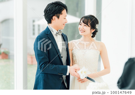 結婚式でケーキ入刀をする新郎新婦(ウェディングケーキ・ケーキカット) 100147649