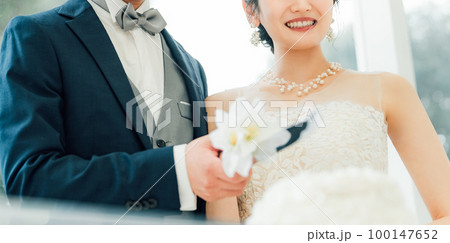 結婚式でケーキ入刀をする新郎新婦(ウェディングケーキ・ケーキカット) 100147652