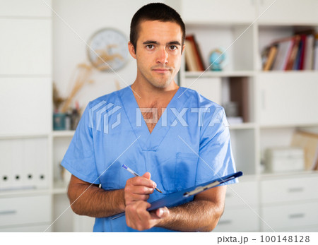 Male nurse filling out medical form on clipboard Male nurse filling out medical form on clipboard 100148128