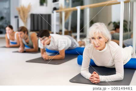 Group of different people doing exercises with roller 100149461