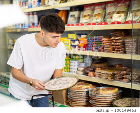 Guy choosing frozen pizza for dinner at grocery store Guy choosing frozen pizza for dinner at grocery store 100149463