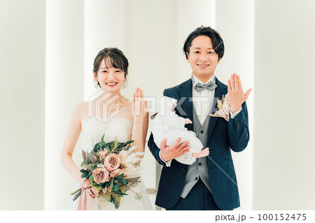 結婚式場で赤ちゃんと一緒に結婚式をあげる新郎新婦（指輪交換・授かり婚・おめでた婚・パパママ婚） 100152475