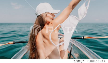 Woman in kayak back view. Happy young woman with long hair floating in transparent kayak on the crystal clear sea. Summer holiday vacation and cheerful female people relaxing having fun on the boat Woman in kayak back view. Happy young woman with long hair floating in transparent kayak on the crystal clear sea. Summer holiday vacation and cheerful female people relaxing having fun on the boat 100153244