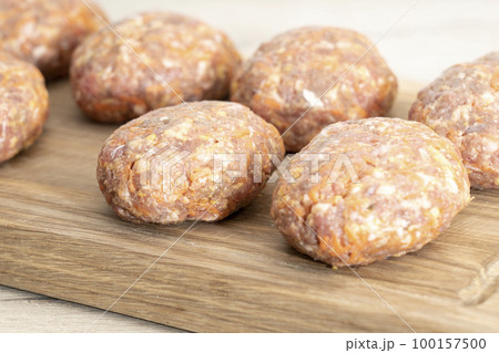 raw homemade meatballs on a massive board made of natural wood raw homemade meatballs on a massive board made of natural wood 100157500