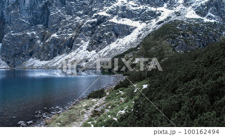 Czarny Staw pod Rysamy or Black Pond lake near the Morskie Oko Snowy Mountain Hut in Polish Tatry mountains, drone view, Zakopane, Poland. 4k Aerial view shot of beautiful green hills and mountains in 100162494